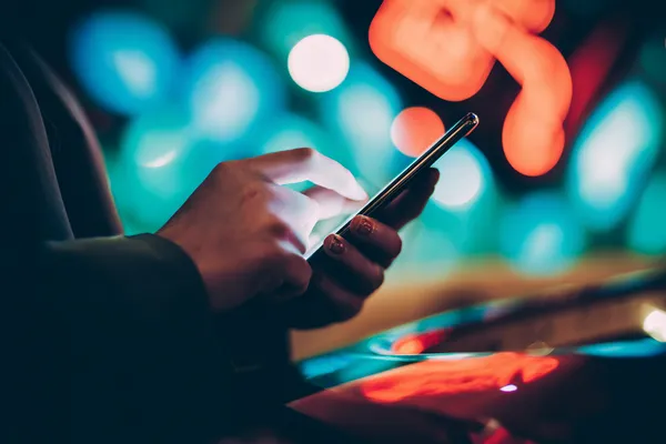 A glamorous woman holding casino chips in a neon-lit environment, representing the premium online casino atmosphere of GOOD111.
