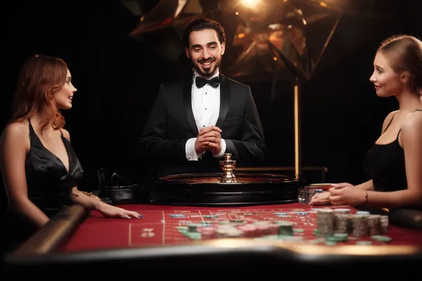 GOOD111 Live Casino — Join thrilling real-dealer tables A professional dealer in a tuxedo greeting players at the roulette table, symbolizing the authentic live casino feel at GOOD111.