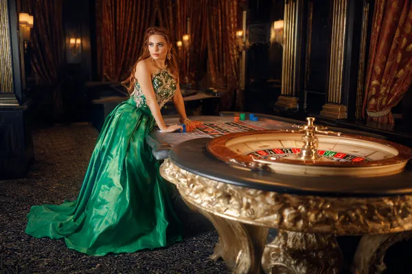 GOOD111 — A high-class gaming experience without limits A woman in a luxurious green gown next to an ornate roulette wheel, capturing the upscale casino mood of GOOD111.